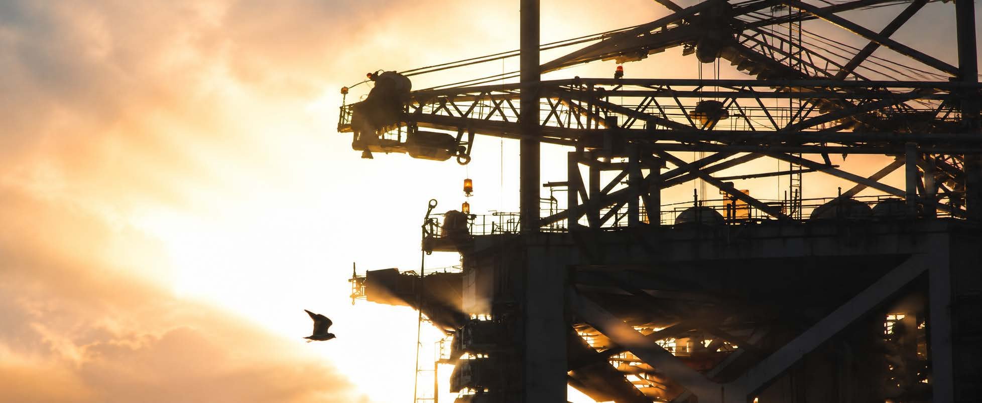 Oil rig silhouette at sunset — oil and gas sector, South Rumaylah fields